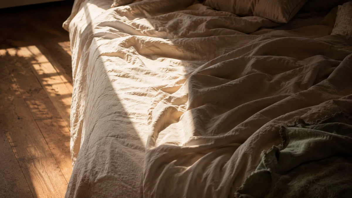 Why Readiness Can Take Longer Some Days Sunlight crossing an unmade linen bed, an empty quiet moment representing how readiness shifts from day to day.
